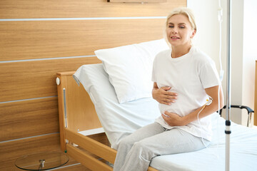 Pregnant woman on medical bed embracing her belly in maternity hospital