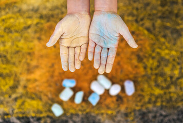 Ukrainian girl, child shows dirty, smeared hands with chalk after drawing yellow-blue on the asphalt, with the flag of Ukraine. Photography, portrait, request for help, poverty, misery, donation.