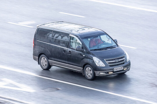 Hyundai H1 minibus is driving on the street, aerial front side view. Light commercial vehicle in motion