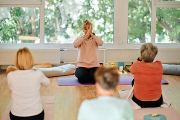A group of senior women engage in various yoga exercises, including neck, back, and leg stretches, under the guidance of a trainer in a sunlit space, promoting well-being and harmony