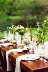 Decoration of wedding table with crystal vases, flowers and branches in botanical style