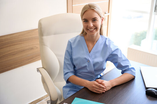 Young Smiling Female Doctor Or Nurse At Working Desk Looking At Camera