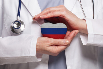 Russian doctor holding heart with flag of Russia background. Healthcare, charity, insurance and...