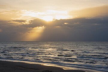 Fototapeta premium Scenic seascape with rays of light shining through the sky.