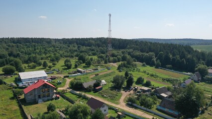 Cell tower in rural area surrounded by forest. Satellite communication and Internet in a countryside settlement, village. Transmitter of cellular communication.