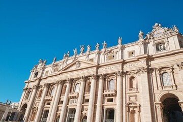 Fototapeta na wymiar View of Saint Peter's Basilica and it's facade detail with Corinthian order columns and blue sky, Rome, Italy