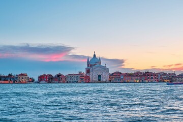 A beautiful shot of the Il Redentore and Santissimo Cathedral across the water at sunset, Venice,...