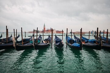 Fototapeta premium Traditional gondolas with the bell tower of the Saint Giorgio Maggiore Church on background (view from San Marco), Venice, Italy