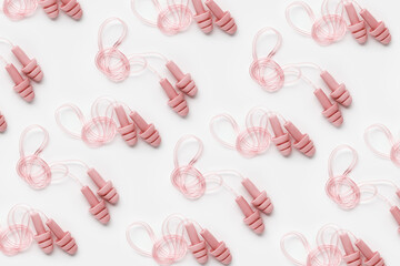 Creative flat lay pattern made powder pink silicone earplugs for swim, sleep, rest on white...