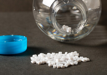 A plastic bottle of water and polymer pellets are nearby