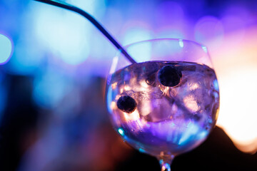 Close-up of Gin and tonic cocktail with blueberries, illuminated by enchanting multicolored lights...