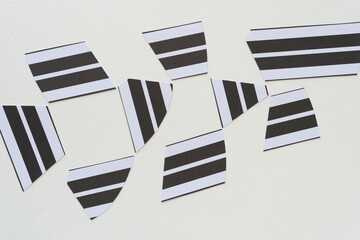 cut black and white paper shapes with striped pattern on blank paper