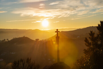 Silhouette one of the numerous medieval cruceiros (calvary) in Ourense against an orange sky. - 714069038