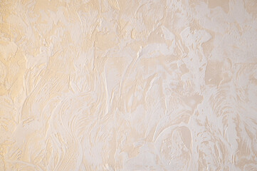 Wall with decorative plaster. Gold glossy plated with white relief pattern.	
