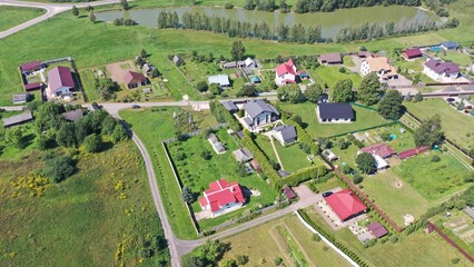 Aerial view of a rural settlement, a village in a valley, in a lowland with a pond in the middle of a picturesque forest and mountains in Europe. Lake, pond in the village in summer.