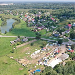 Aerial view of a rural settlement, a village in a valley, in a lowland with a pond in the middle of a picturesque forest and mountains in Europe. Lake, pond in the village in summer.