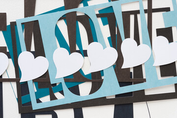 row of white hearts on a pile of machine-cut stencils with the word 