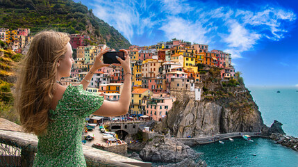 .A tourist girl taking a picture of Manarola, Liguria, Italy - obrazy, fototapety, plakaty