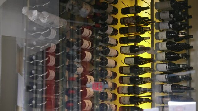 Unique cellar with glass panel for convenient viewing including bottles of wine containing different types and colors of beverage. Concept of storage of drinks