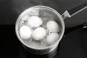 Fototapeta na wymiar Chicken eggs boiling in saucepan on electric stove, above view