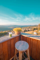 A view of the hill from the coffee shop, including a sunset in the background and a wooden chair placed into a corner. 