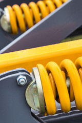 Yellow hard spring made of steel. Part of big industrial or agricultural machine