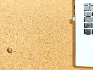 Laptop on the sand, indicating the concept that electronic devices are made of silicon which have sand as raw material