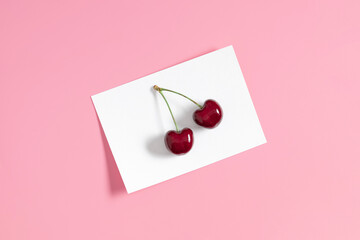 Empty postcard mockup and cherry fruit on pink background. Mockup with postcard and berries. Flat lay, top view, copy space