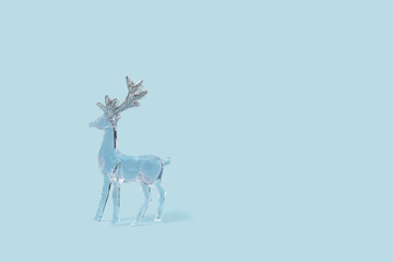 Glass deer on blue background. Creative concept with copy space.