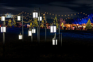 Square lanterns in the forefront with holiday Christmas trees and lights in the background