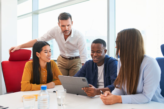 Diverse team discussing business project on digital tablet at office during informal meeting
