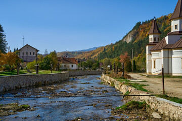 Fototapeta na wymiar River running through a small village in the rural Transylvania region of Romania on a fall day with autumn colors