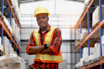 Portrait of young African worker man wearing safety vest and helmet, standing with arms crossed at...