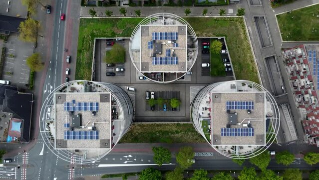 Aerial top down view of three modern apartment buildings located in Hilversum the Netherlands showing the real estate property roofs and solar panels streets with traffic around the complex 4k