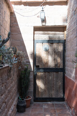 Vertical de puerta rústica antigua con madera y hierro en ingreso vivienda y muros de ladrillo con macetas y plantas