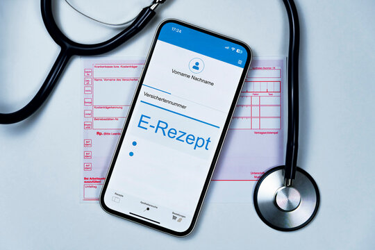 Smartphone mit e Rezept auf dem Display liegt auf herkömmlichen Kassenrezept, ein Stethoskop liegt daneben, horizontal, weißer Hintergrund 