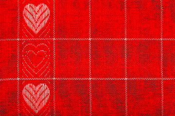 Embroidered abstract pattern with hearts on a red cloth.  Valentines day background. Copy space for text