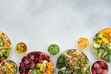 Preparing fresh vegetables in summer for winter, various frozen vegetables and berries in plates on a gray background, top view, copy space - obrazy, fototapety, plakaty