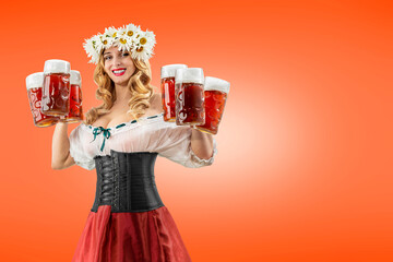Midsummer woman waitress serving big beer mugs on orange isolated background. Blonde girl with...