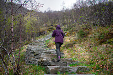 Obraz premium Female hiker climbing Old stone staircase once used by ancient monks. Reine, Lofoten, Norway