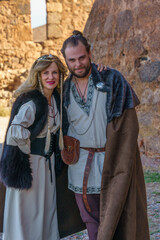 Smiling Couple in Medieval Clothing with Castle Ruins