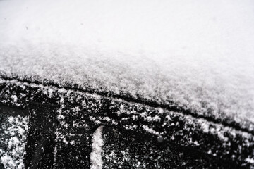 toit et porte de voiture noire sous la neige, en gros plan