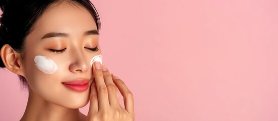 Asian woman applies cream to hydrate and smooth her skin, promoting beauty and wellness. - obrazy, fototapety, plakaty