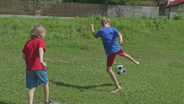 Children play football, happy boys playing soccer. Slow motion.
Cute Boys are playing football on grass near mountain river.