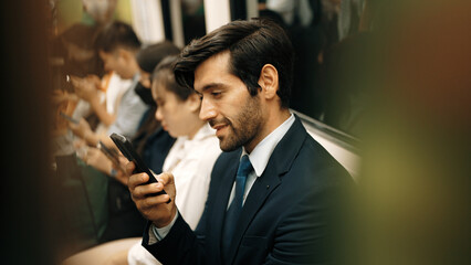 Smiling caucasian business man looking at mobile phone or playing social media while sitting in...
