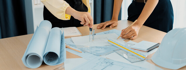 Professional architect team used divider measure during draft blueprint on table with architectural...
