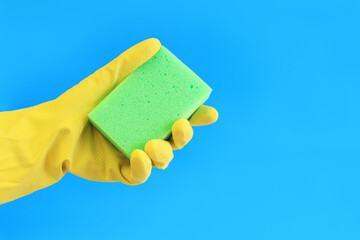 Female hand in latex gloves hold sponge for washing dishes. Cleaning the premises. Professional cleaning. Household gloves, yellow. Cleaning woman
