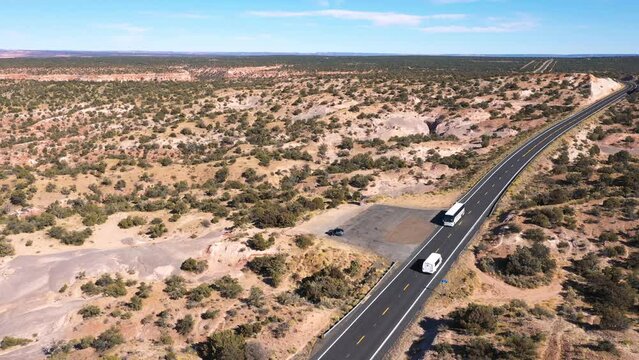 Passenger commercial tour bus and minibus driving along asphalt highway with yellow markings in desert prairie of Usa. Transportation of goods or tourists by intercity road. Aerial view in motion