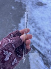 hand holds icicle , freezing water