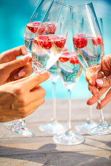 Hands with Champagne glasses with raspberry